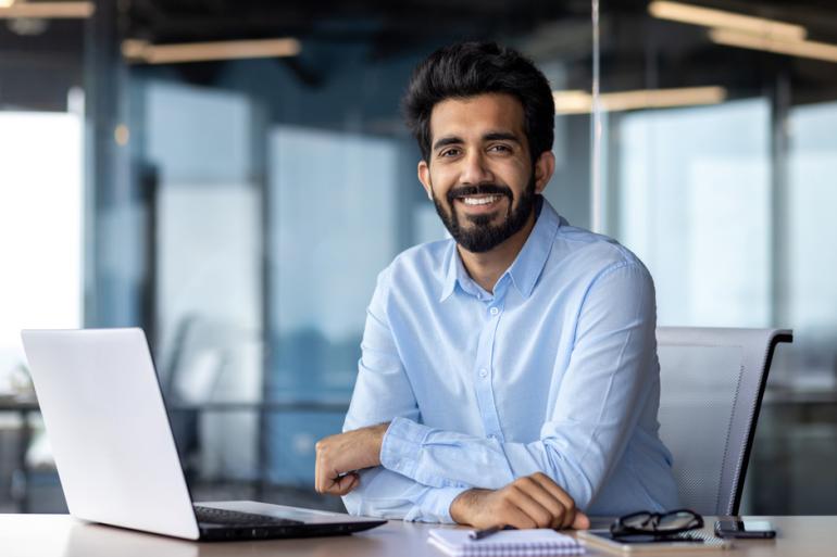 Hombre sonriendo frente a un computador